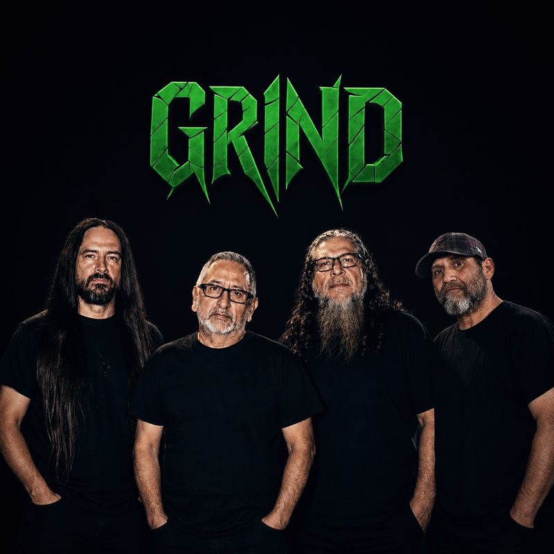 The four members of GRIND standing in black shirts against a dark backdrop beneath the green cracked GRIND logo